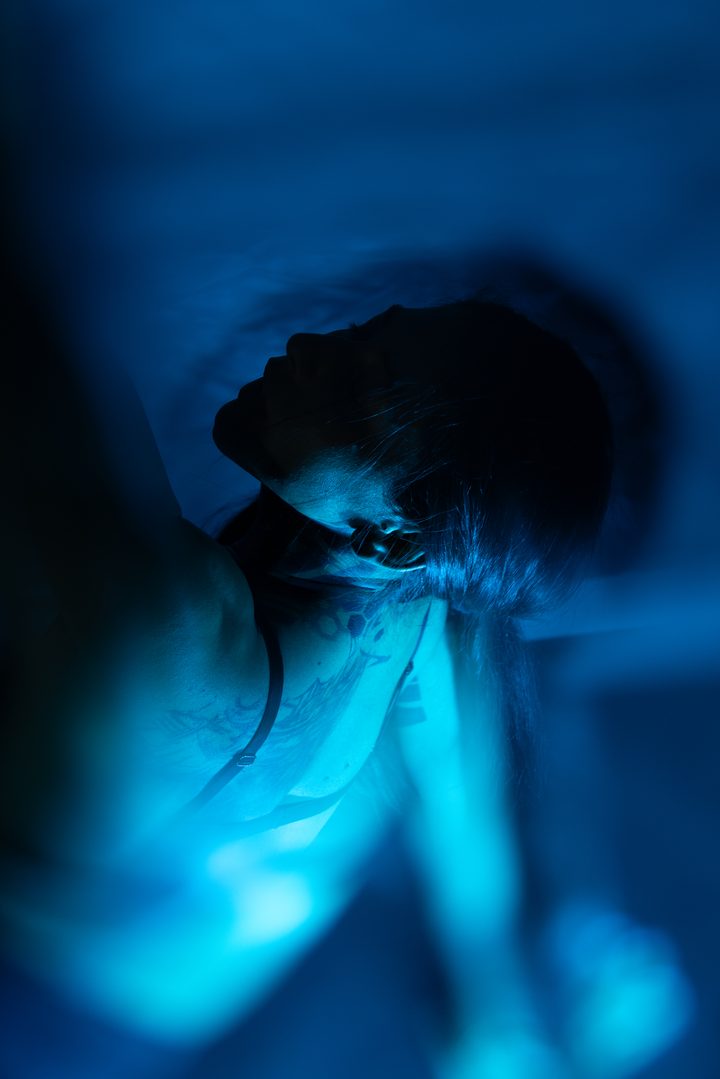 A standing figure pulled into vertical streaks of red and amber by a long exposure, the body almost wholly abstract.