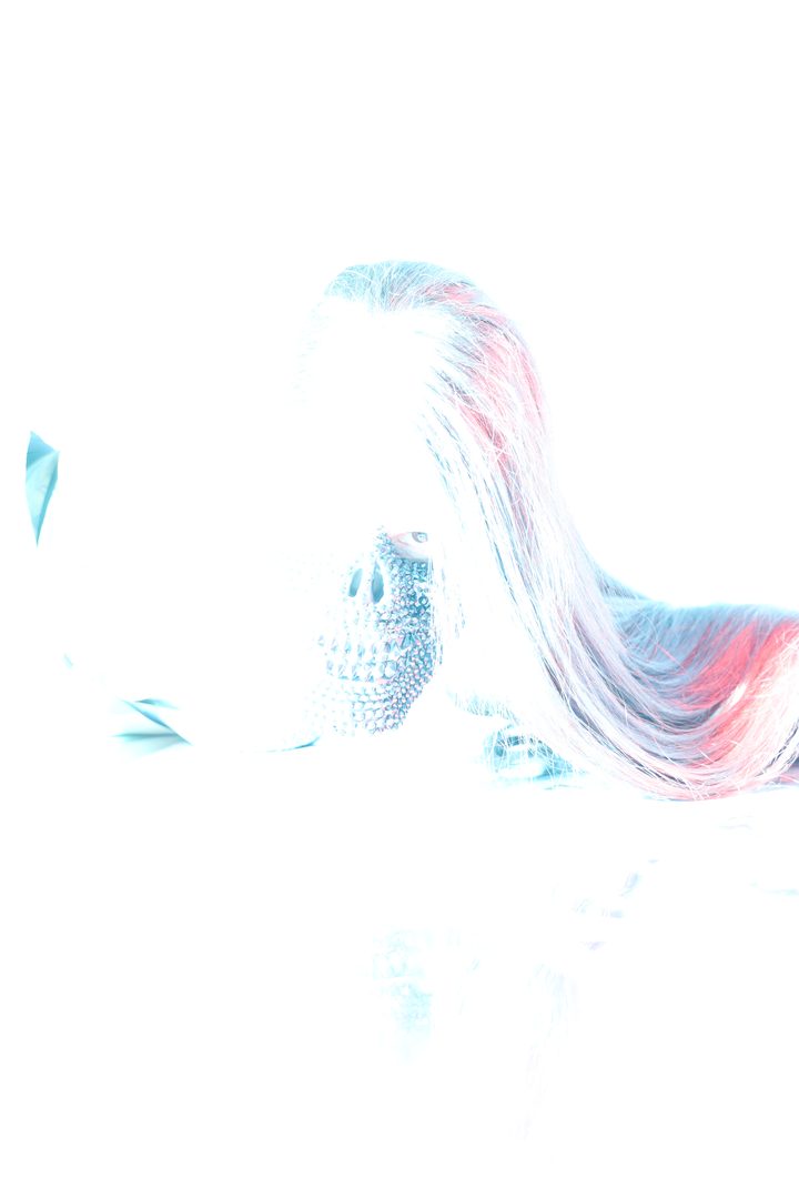 A figure on a bright, blown-out ground in cool blue light, long hair caught in motion and crossing the frame.